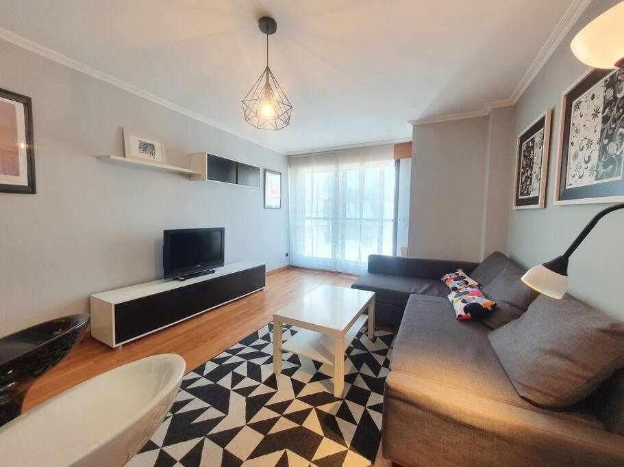 uma sala de estar com um sofá e uma mesa em Apartamento Playa Jardín em Ribeira