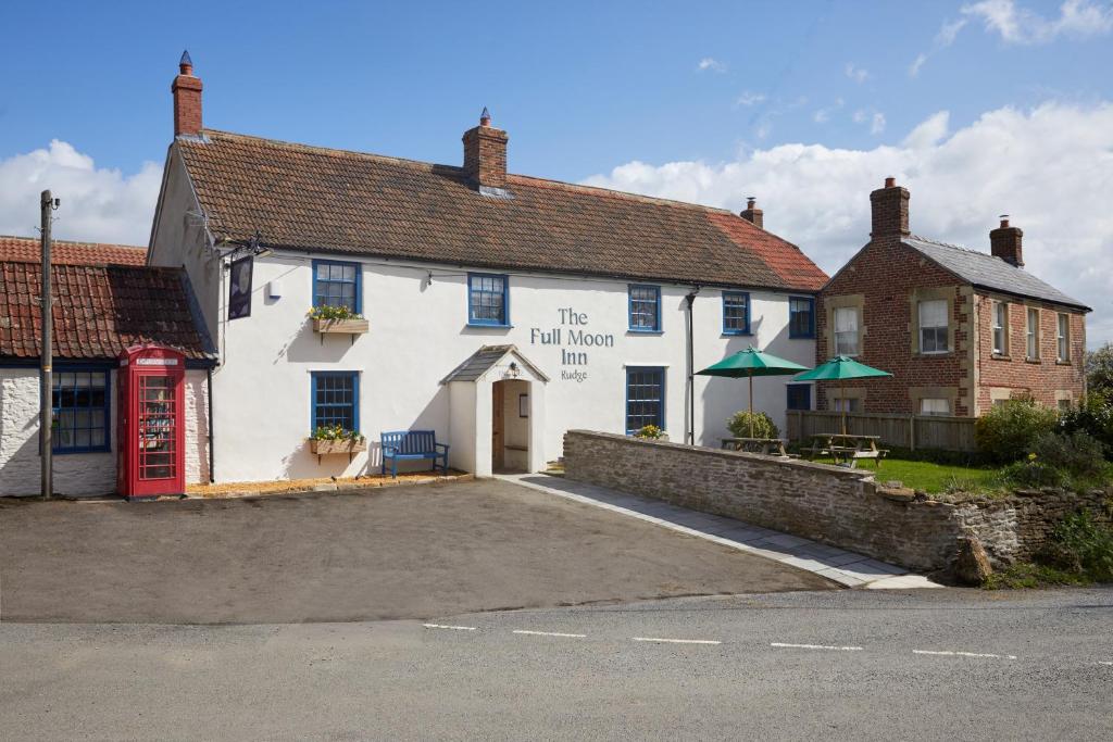 ein weißes Gebäude mit einer roten Tür neben einer Straße in der Unterkunft Full Moon Inn Rudge in Frome