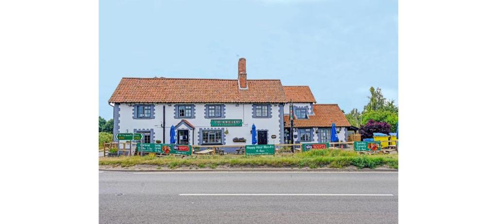 a white house sitting on the side of the road at OYO The Billingford Horseshoes in Scole