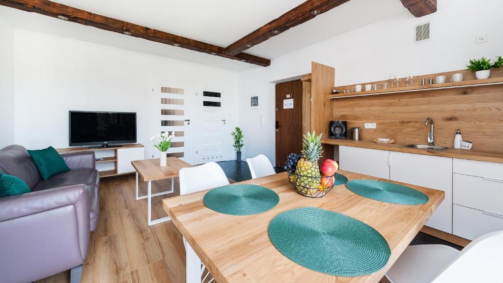 a kitchen and living room with a wooden table at Apartamenty Sun & Snow Kościelisko Residence in Kościelisko