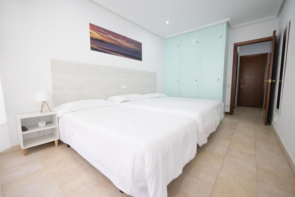 a white bedroom with a large white bed in it at Hotel Pinar Somo Surf in Somo