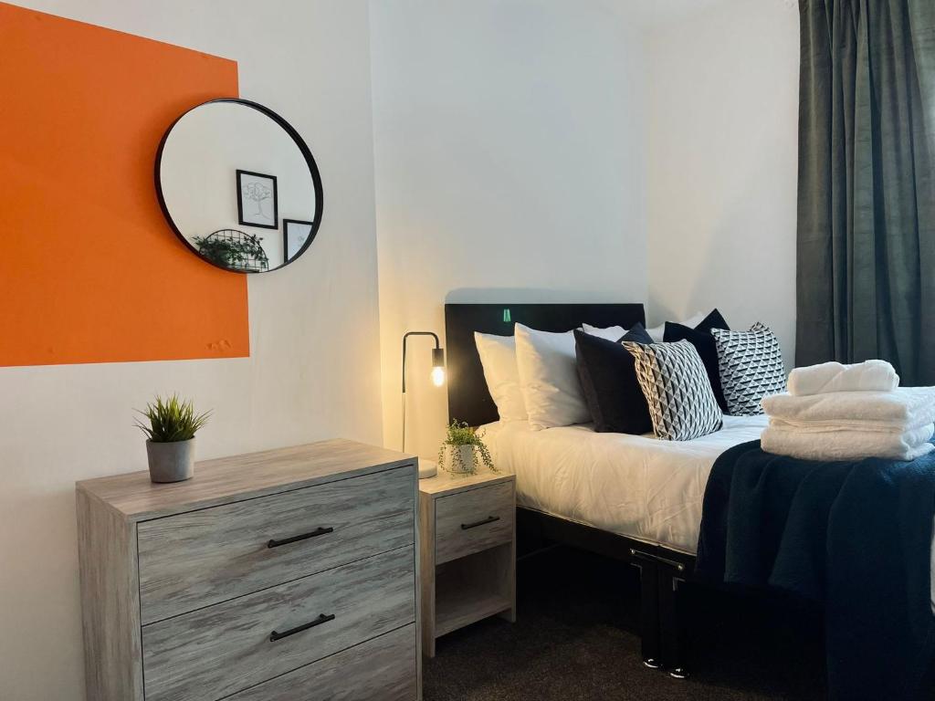 a bedroom with a bed and a mirror and a dresser at Taff Valley Heartwarming Cottage In Aberafan Merthyr Tydfil By STAE-Homes in Merthyr Tydfil