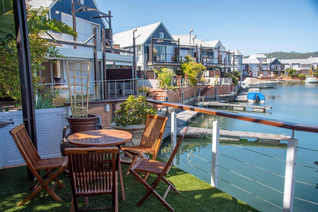 a table and chairs on a balcony overlooking a river at WATERFRONT 2 Bed Home with mooring at Knysna Quays in Knysna