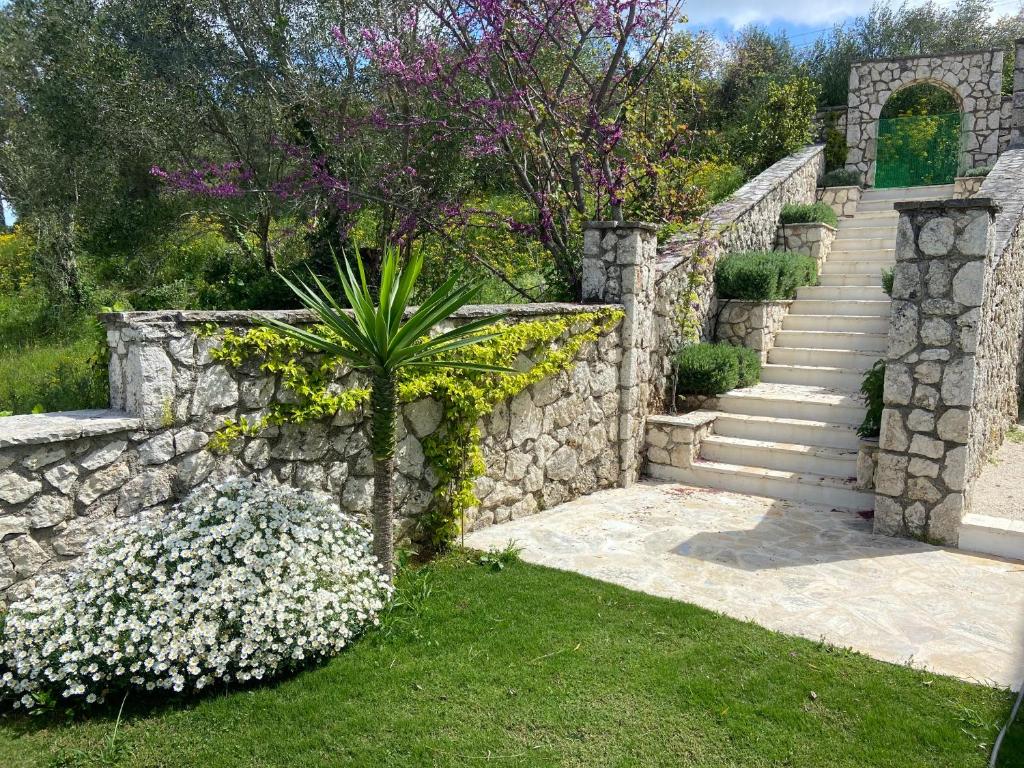 a stone wall with stairs and flowers in a yard at Villa by the Lake in Karoubatika near Agios Ioannis in Agios Ioannis