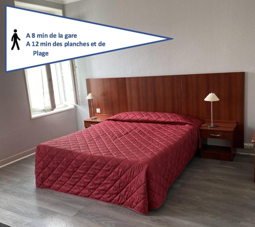 een slaapkamer met een groot bed en een rood dekbed bij Hotel des Sports in Deauville