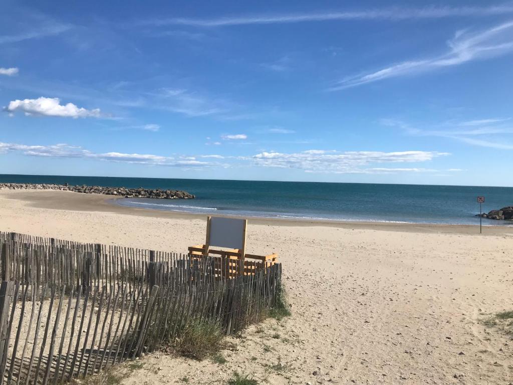 - une plage avec une clôture et une chaise dans l'établissement Appartement en bord de plage serviettes non incluses, à Frontignan