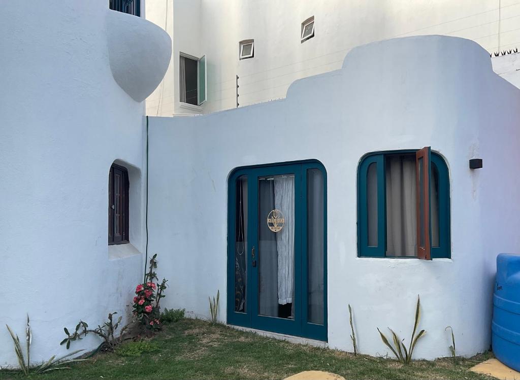 een wit gebouw met een blauwe deur en ramen bij Villa Oasis-Studio Room in Puerto Vallarta