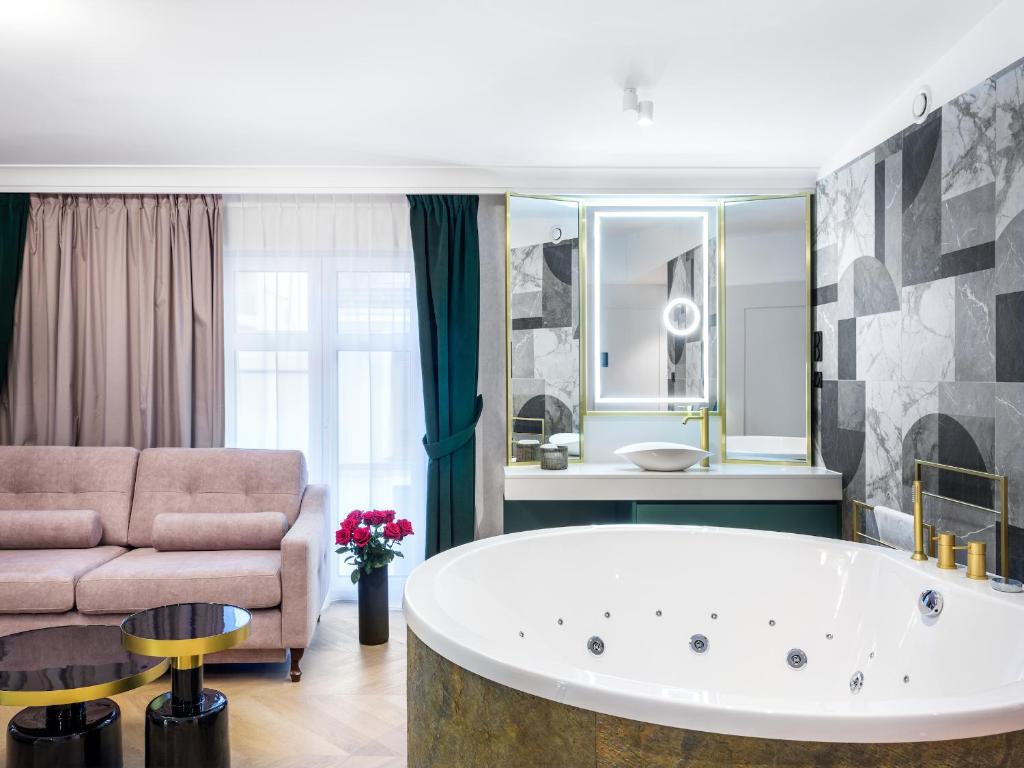 een grote badkamer met een bad en een bank bij Golden Queen Deluxe Jacuzzi Apartments - Old Town in Krakau