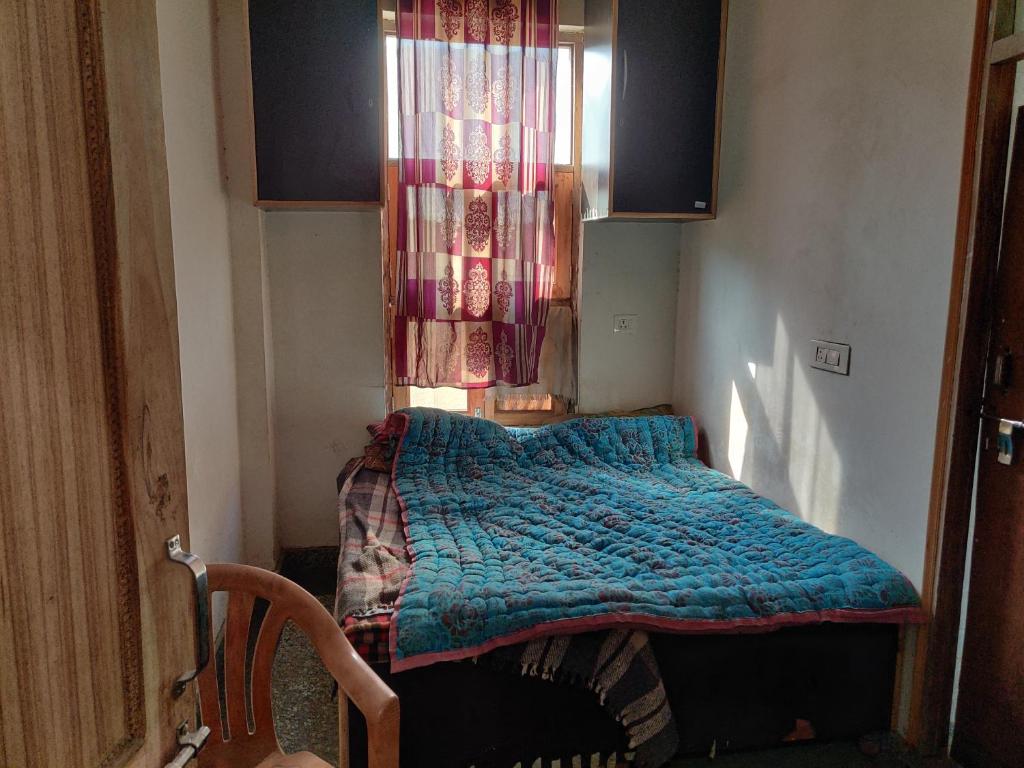 Dormitorio pequeño con cama con edredón azul en Hotel EPS, en Ghaziabad