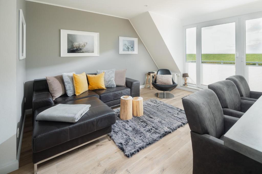 a living room with a black leather couch and a rug at Haus Ebbe & Flut - mit Blick auf das Wattenmeer in Juist