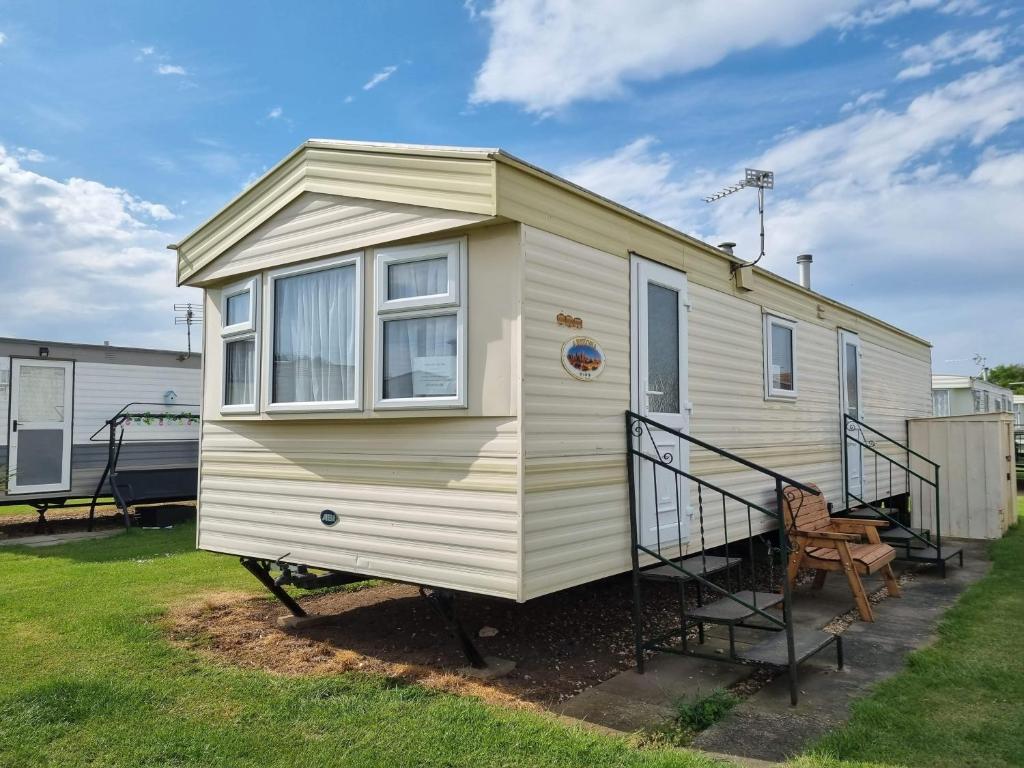 ein winziges Haus auf einem Wohnwagen im Hof in der Unterkunft Caravan Holiday home Happy days south 17 in Chapel Saint Leonards