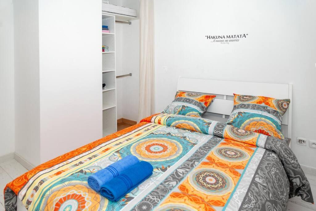 a bedroom with a bed with colorful sheets and pillows at Appartement cosy à 10 min de Disneyland Paris ! in Montévrain