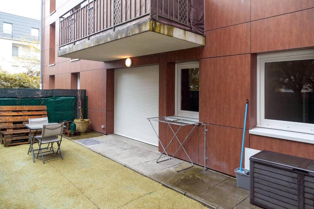 a patio with a table and a balcony on a building at Appartement cosy à 10 min de Disneyland Paris ! in Montévrain