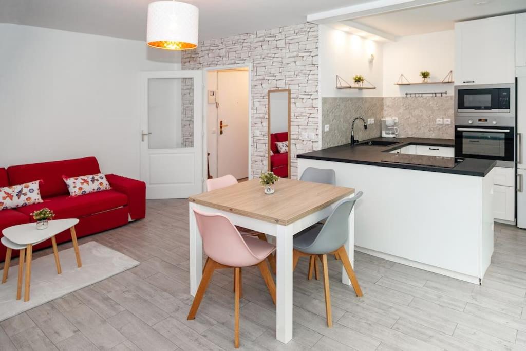 a kitchen and a living room with a table and chairs at Appartement cosy à 10 min de Disneyland Paris ! in Montévrain