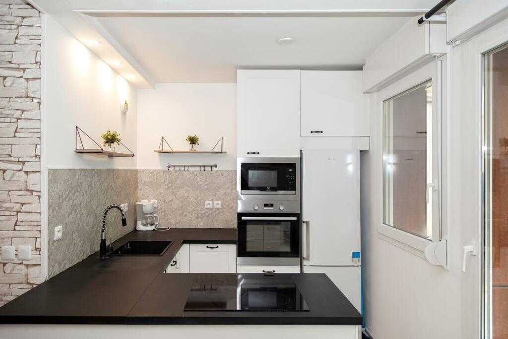 a kitchen with white cabinets and a stove top oven at Appartement cosy à 10 min de Disneyland Paris ! in Montévrain