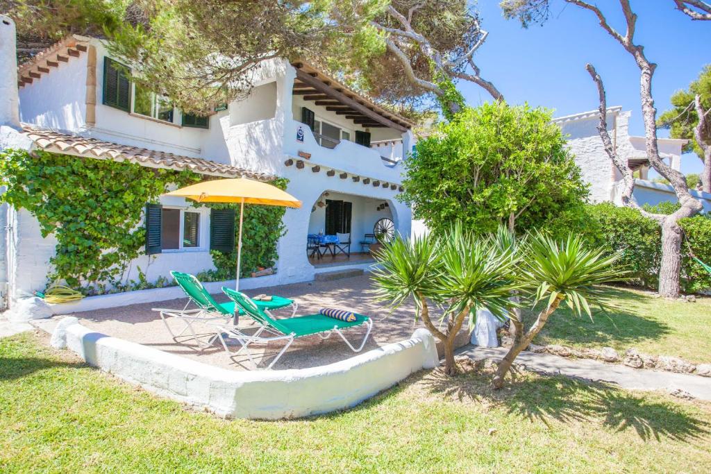 a house with a table and chairs and an umbrella at Voramar Ham in Playa de Muro