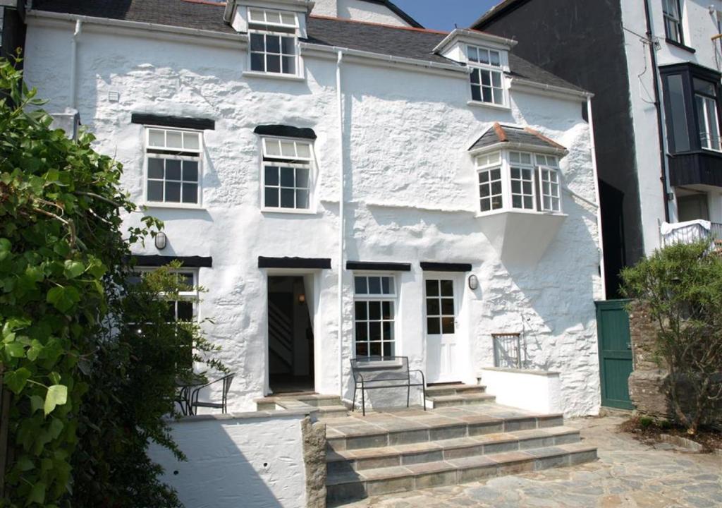 ein weißes Haus mit zwei Stühlen davor in der Unterkunft Stepaside Cottage in Fowey