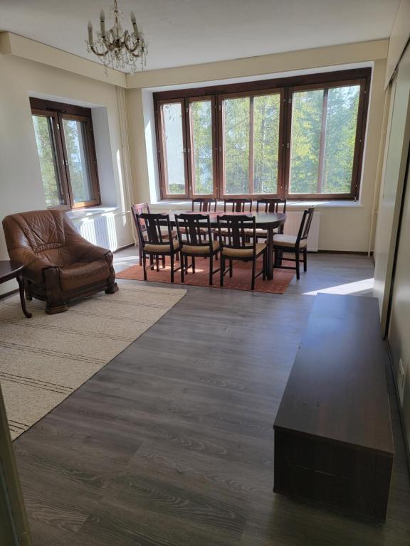 a dining room with a table and chairs and windows at Sunny apartment next to a beautiful lake in the forest in Imatra