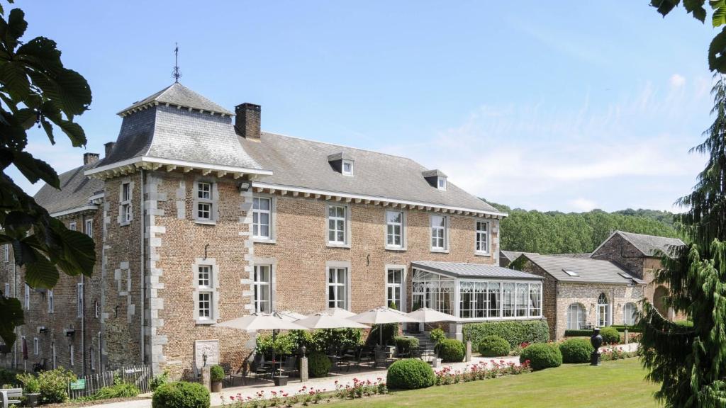 Hof de Draeck Bed & Breakfast في Teuven: مبنى من الطوب كبير مع مظلات أمامه