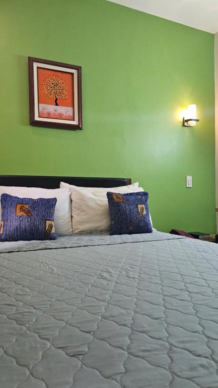 um quarto verde com uma cama grande e almofadas azuis em 20 Studio Hotel em Marikina
