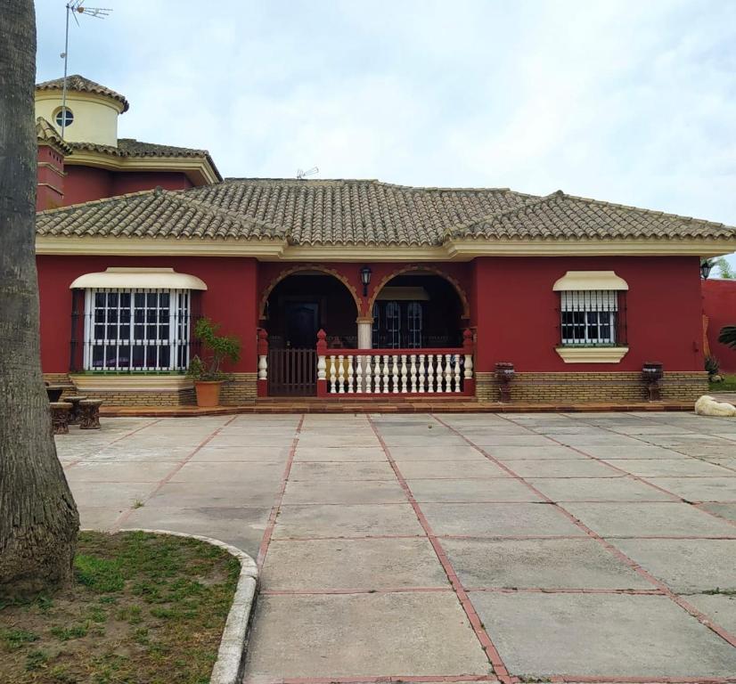 una casa roja con una valla blanca delante de ella en CHALET VACACIONAL a 10 minutos de la playa de La Barrosa, en Chiclana de la Frontera