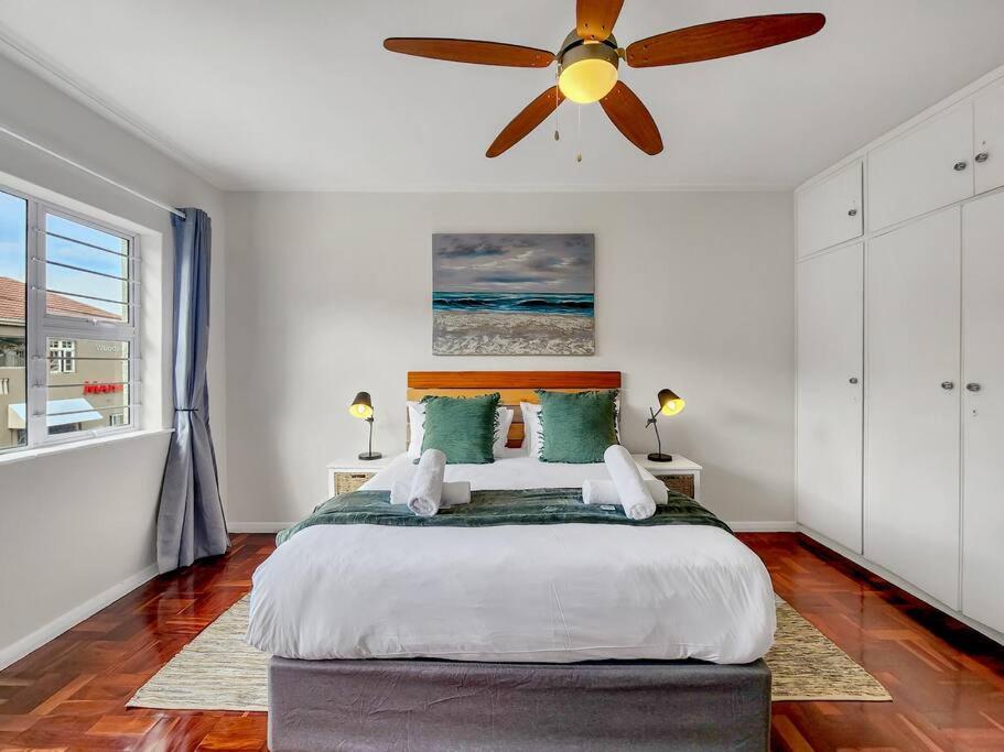 a bedroom with a bed with a ceiling fan at Charming and Sunny Apartment in Cape Town