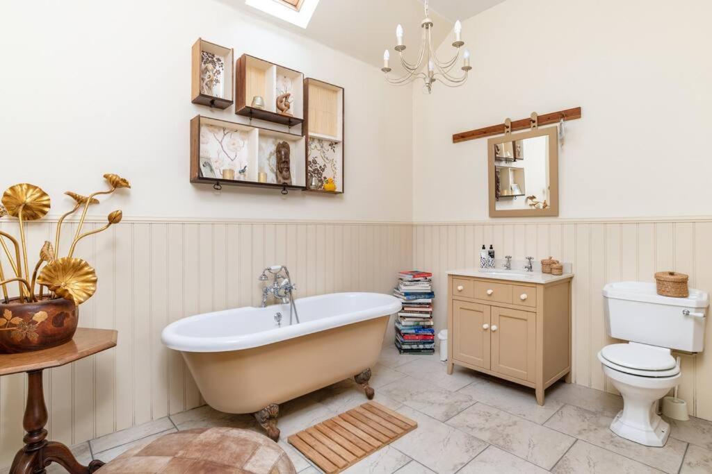 a bathroom with a tub and a toilet and a sink at The Cowshed in Laurencekirk