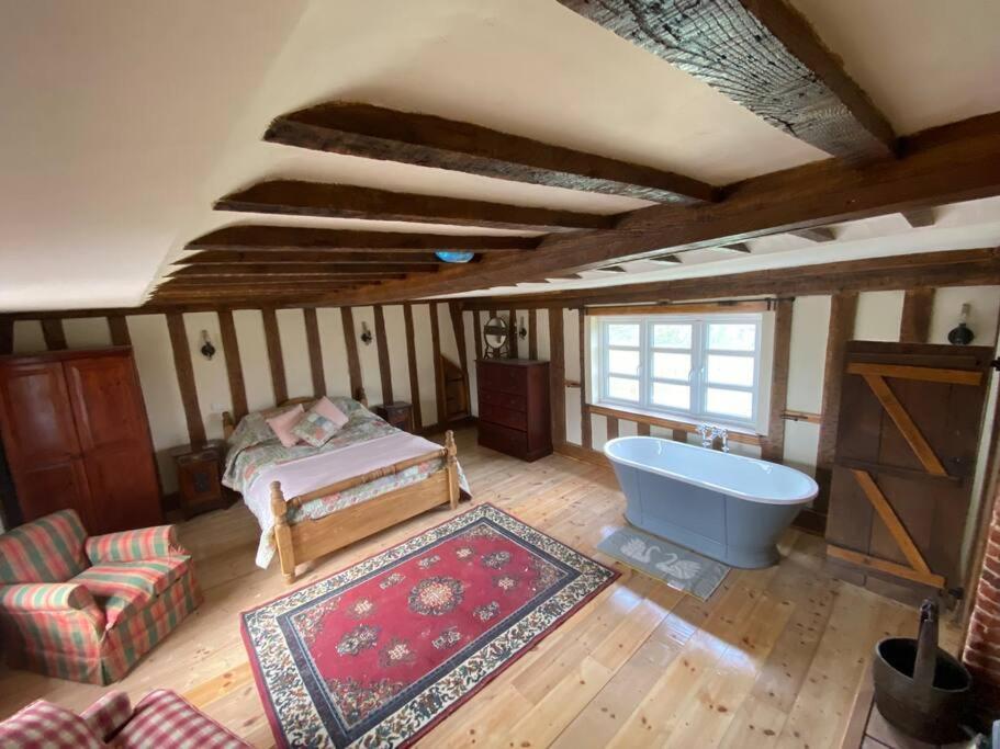 a room with a tub and a bed and a rug at A newly renovated, cosy escape in the beautiful Shepherd's Cottage in East Dereham