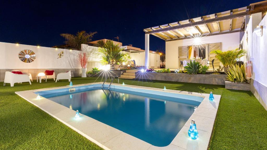 ein Schwimmbad im Garten eines Hauses nachts in der Unterkunft Villa Amatista Salinas Golf & Beach in Caleta de Fuste