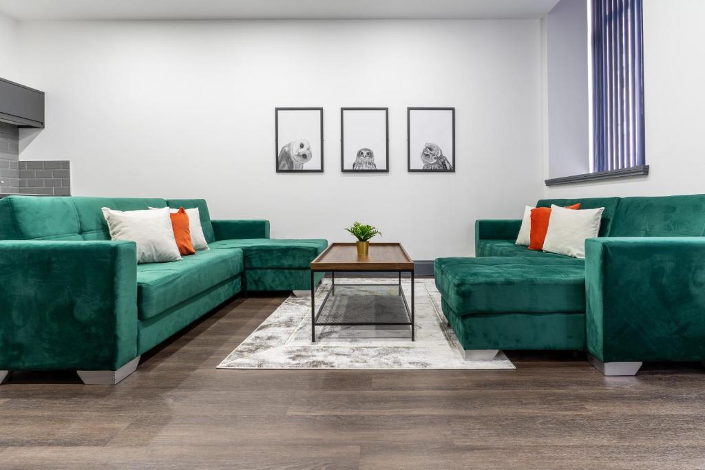 a living room with two green couches and a table at Water Street by Ustay Aparthotels in Liverpool
