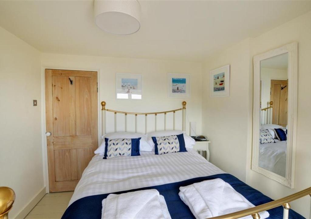 a bedroom with a bed with blue and white pillows at 5 Seaview in Looe