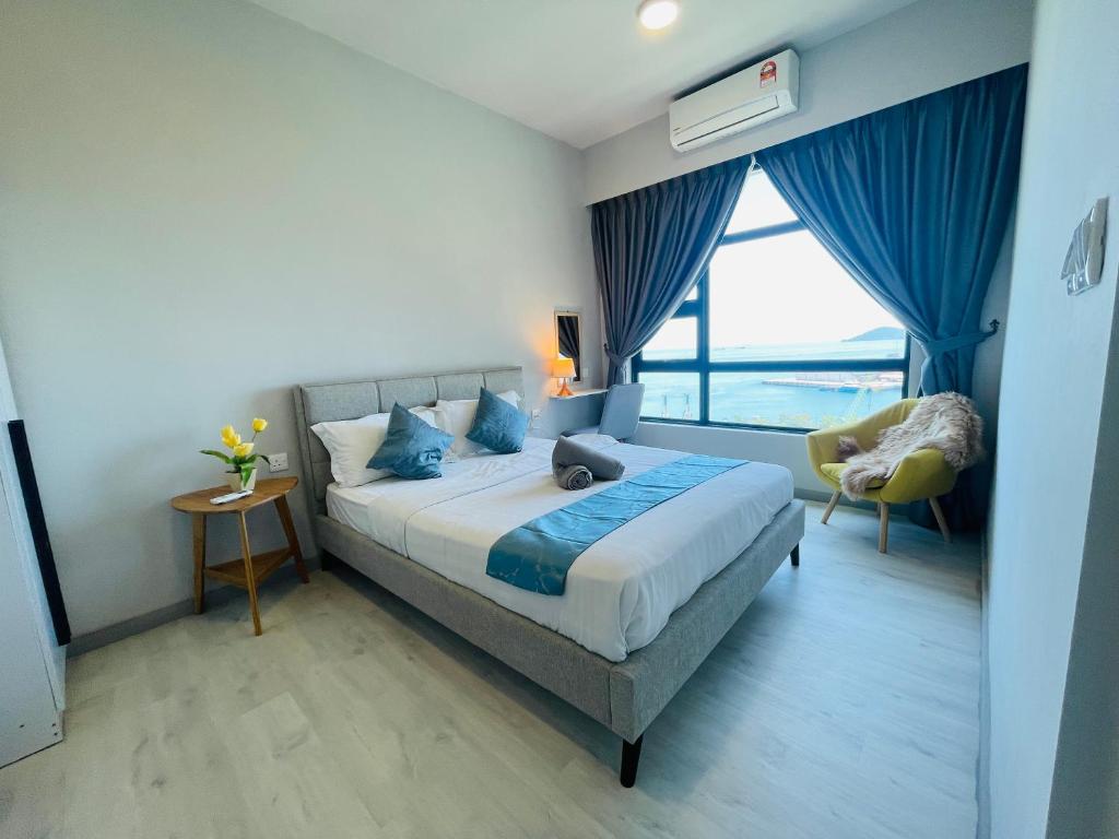 een slaapkamer met een bed, een stoel en een raam bij JQ1 SEA & POOL or CITY View WIFI I WASHING MACHINE for Seaview unit I CUCKOO WATER Jesselton Quay by R2 in Kota Kinabalu