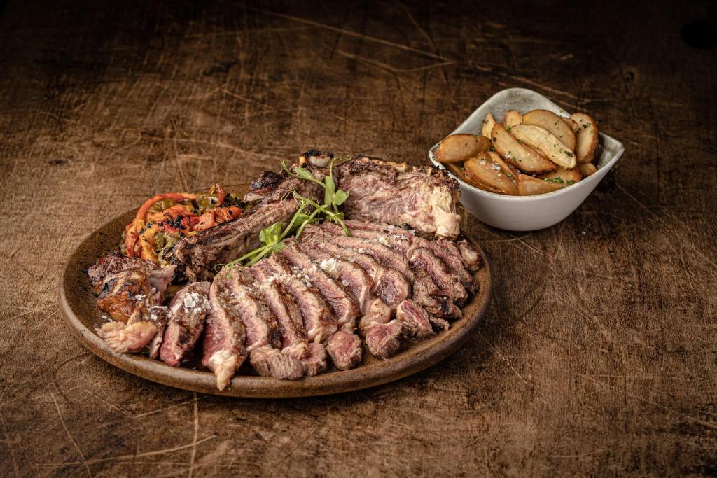 a plate of meat and a bowl of chips on a table at Parque Santiago III Official in Playa de las Americas