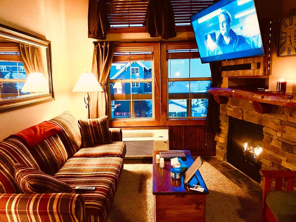 un soggiorno con divano e TV a schermo piatto di In the Heart of the Village Ski In Out a Dunmore