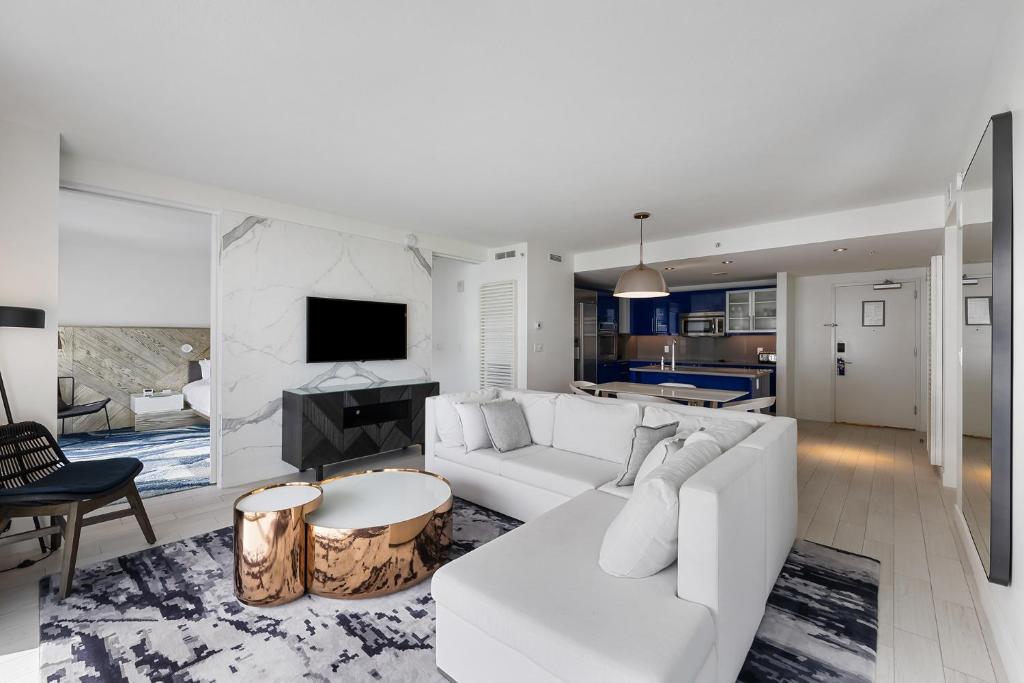 ein Wohnzimmer mit einem weißen Sofa und einem Fernseher in der Unterkunft Resort-Style Residence Beachfront Condo Oasis in Fort Lauderdale