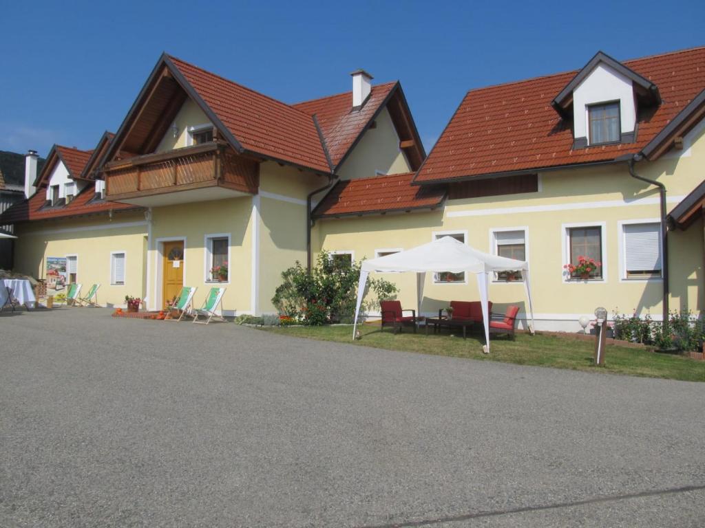 ein Haus mit einem Tisch und einem weißen Regenschirm in der Unterkunft Apfelhof FLIEDER in Kukmirn