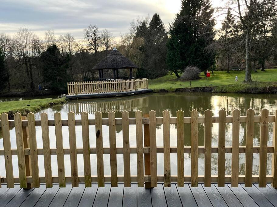 uma cerca em frente a um lago com um gazebo em Blackbrook Lodge Cabin em Turnditch