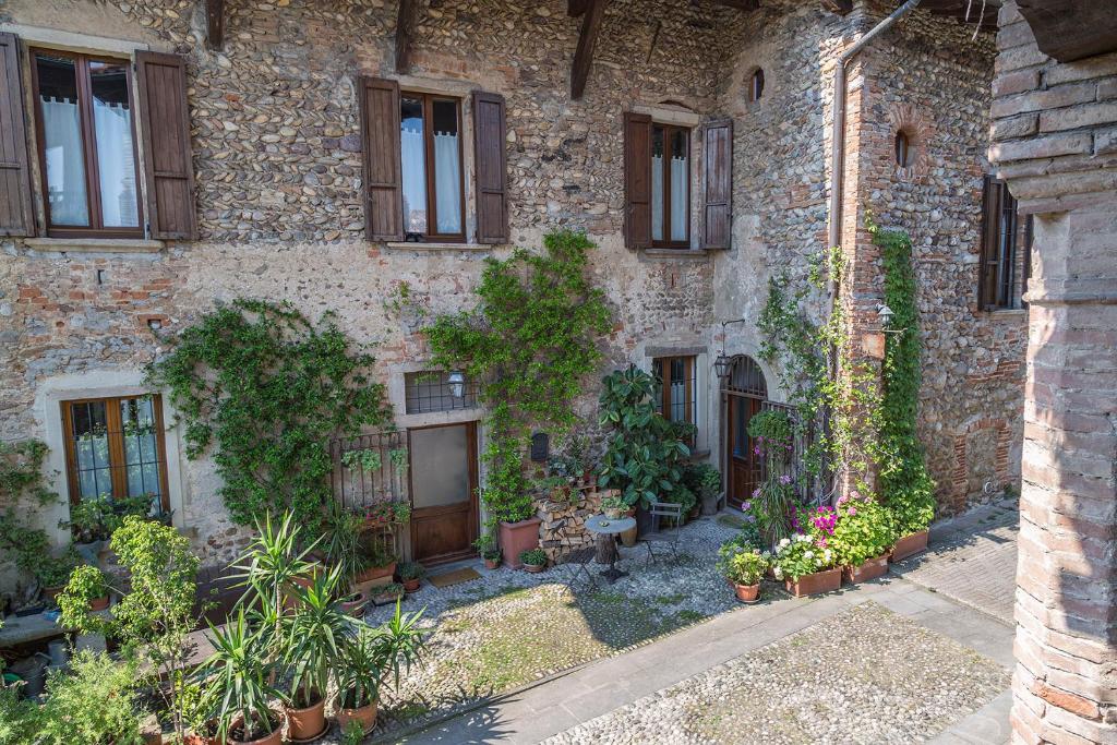 een oud stenen gebouw met planten en ramen bij La Locanda della Torre in Marne di Filago