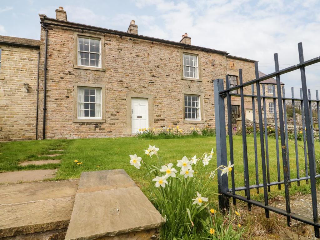 an old brick building with a gate and flowers at Covercote in Leyburn