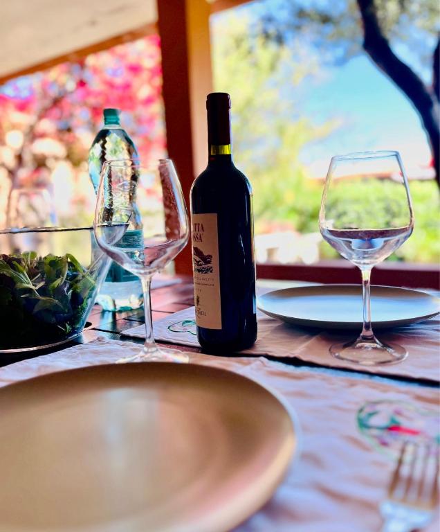 a bottle of wine and two glasses on a table at 20 steps from the beach VILLINO STECU in Costa Rei