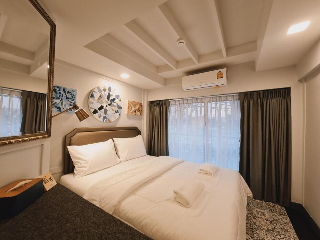 a bedroom with a large white bed with a window at Suraya Bangkok in Bangkok