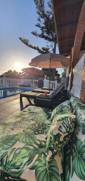 a patio with lounge chairs and umbrellas on a deck at Villa Don Giovanni Fuengirola, Piscina Privada y vistas al mar y a la Montaña in Fuengirola
