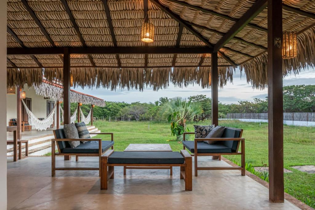a patio with chairs and a table and a hammock at Villa Estrelas Atins in Atins