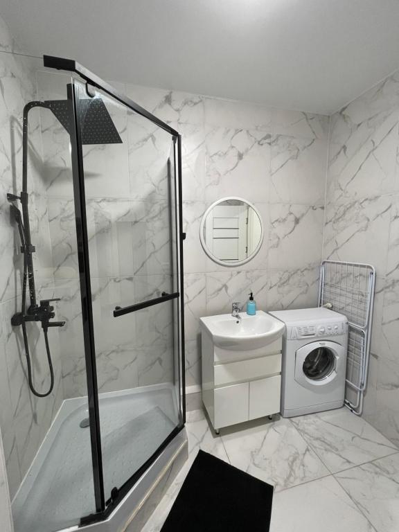 uma casa de banho com um chuveiro, um lavatório e uma máquina de lavar roupa em Квартира в новому ЖК Svitlo Park Київ em Kiev