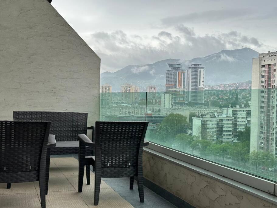 d'un balcon avec deux chaises, une table et une grande fenêtre. dans l'établissement Cityscape Penthouse, à Sarajevo
