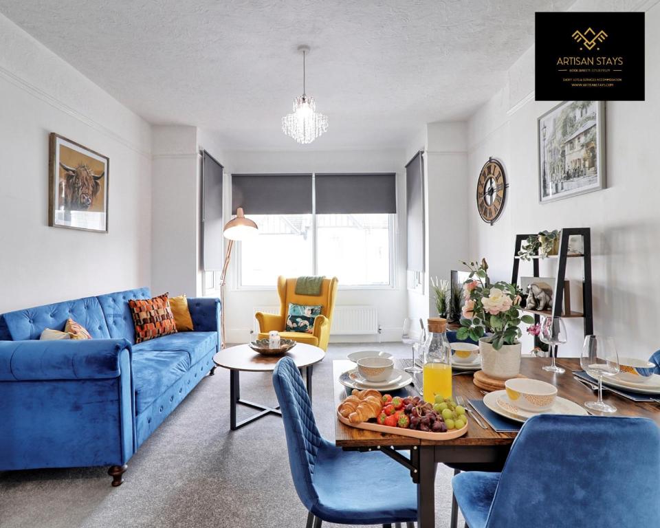 a living room with a table and a blue couch at Deluxe Apartment in Southend-On-Sea by Artisan Stays I Long Stay Offer I Relocation or Business in Southend-on-Sea