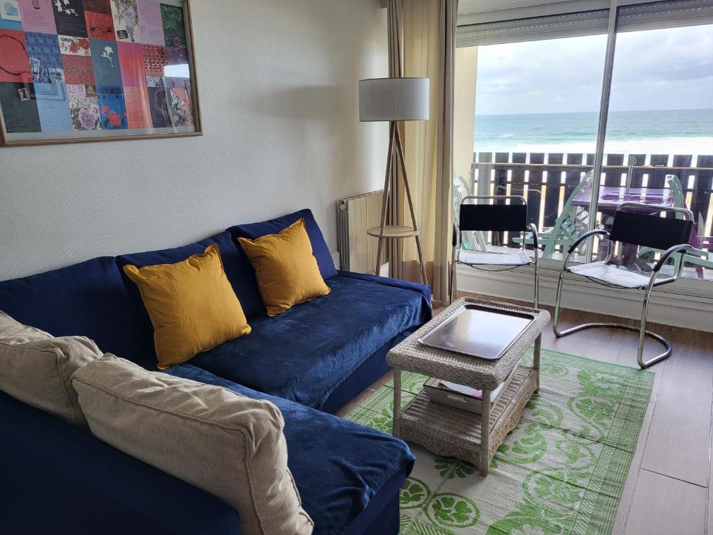 a living room with a blue couch and a view of the ocean at Ocean View Oceanide in Lacanau-Océan