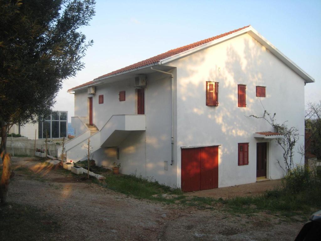 a white house with red doors and windows at Apartments Zmaj in Zavala