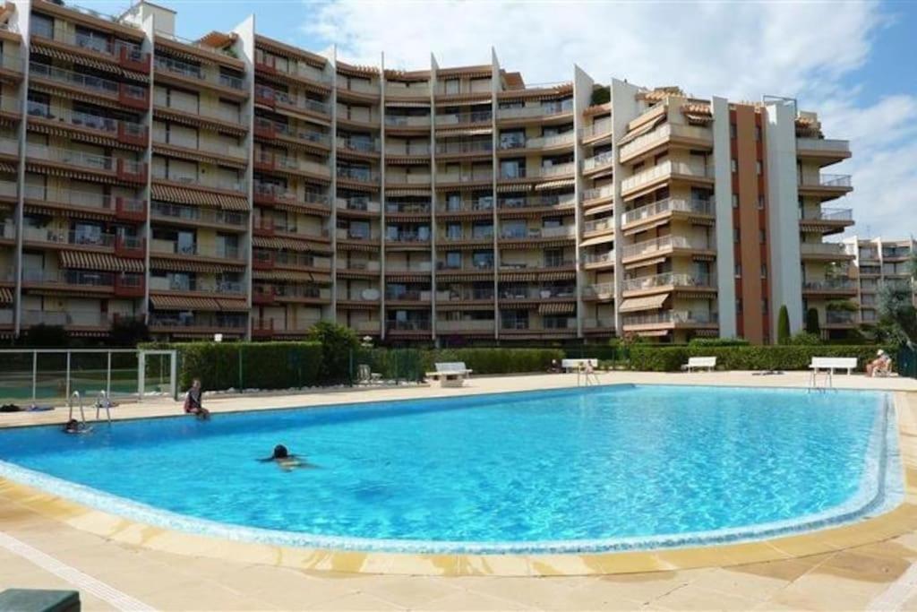 une grande piscine en face d'un grand immeuble dans l'établissement Joli Studio avec piscine, à Mandelieu-la-Napoule