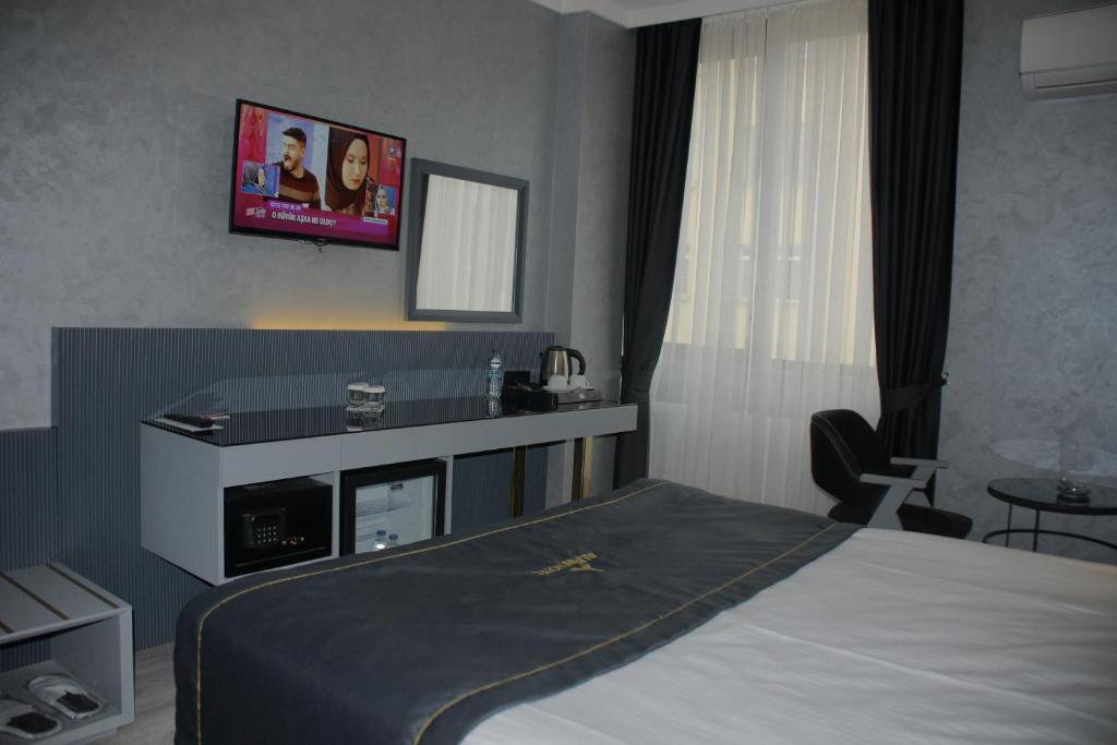 a bedroom with a bed and a tv on the wall at Alfin Hotel in Ankara